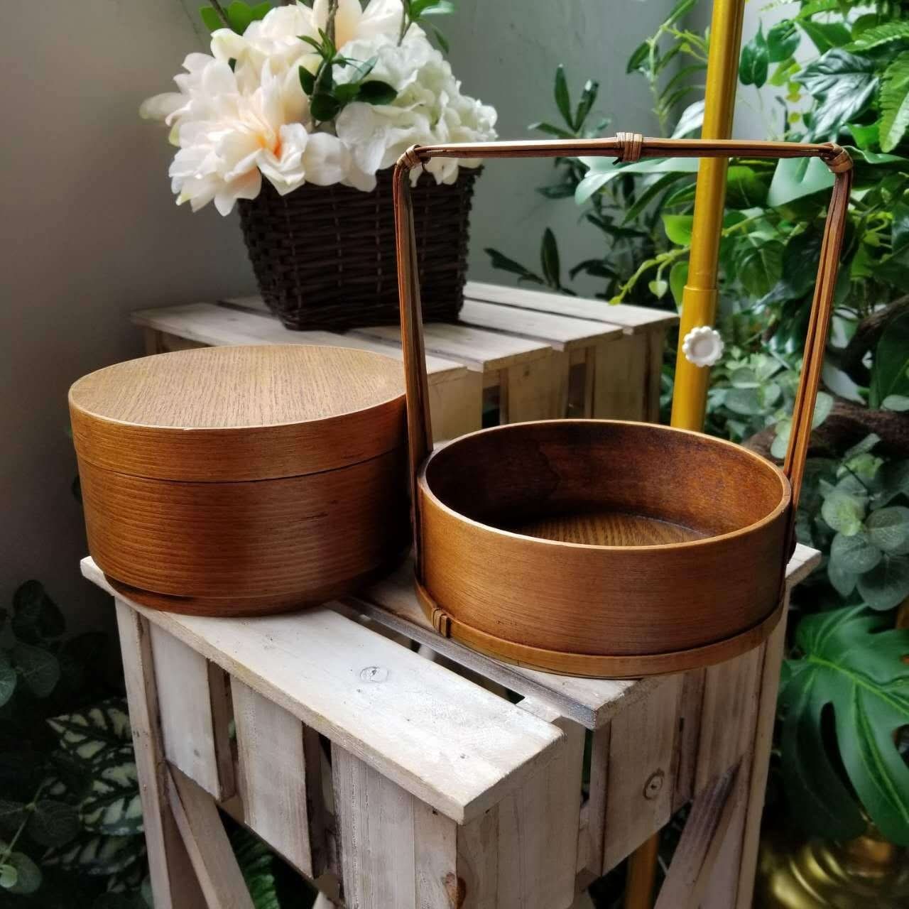 Round wooden Japanese lunch box with a handle on a rustic table, home decor.